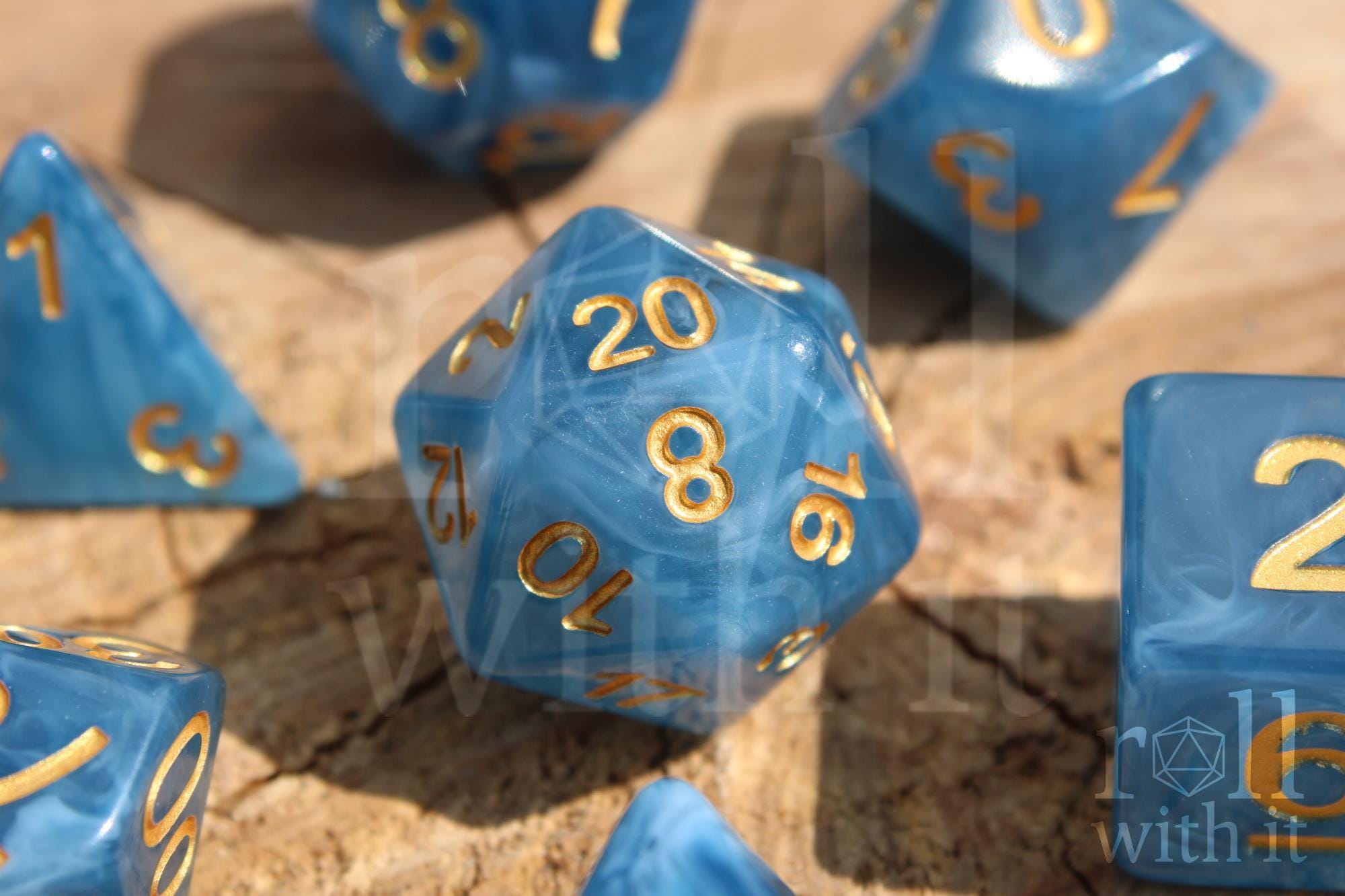Set of jade blue translucent polyhedral roleplaying dice with gold numbers on a wooden surface