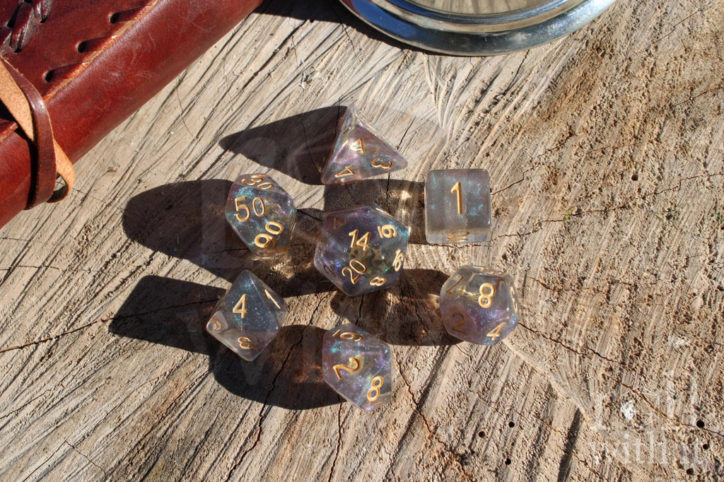 Set of iridescent glittery and star like role playing DnD dice with gold numbers and golden cogs inside on a wooden surface