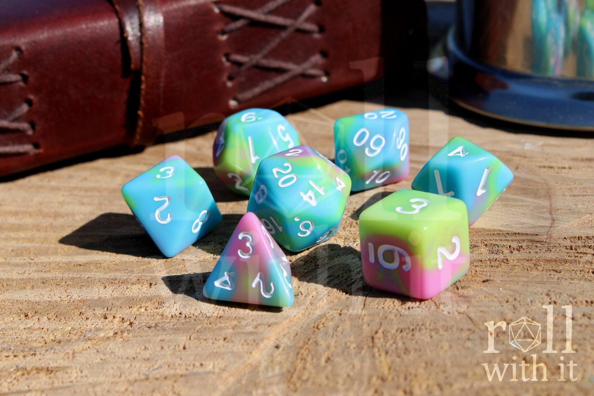 Set of colourful pastel rainbow polyhedral DND roleplaying dice with white numbers on a wooden surface