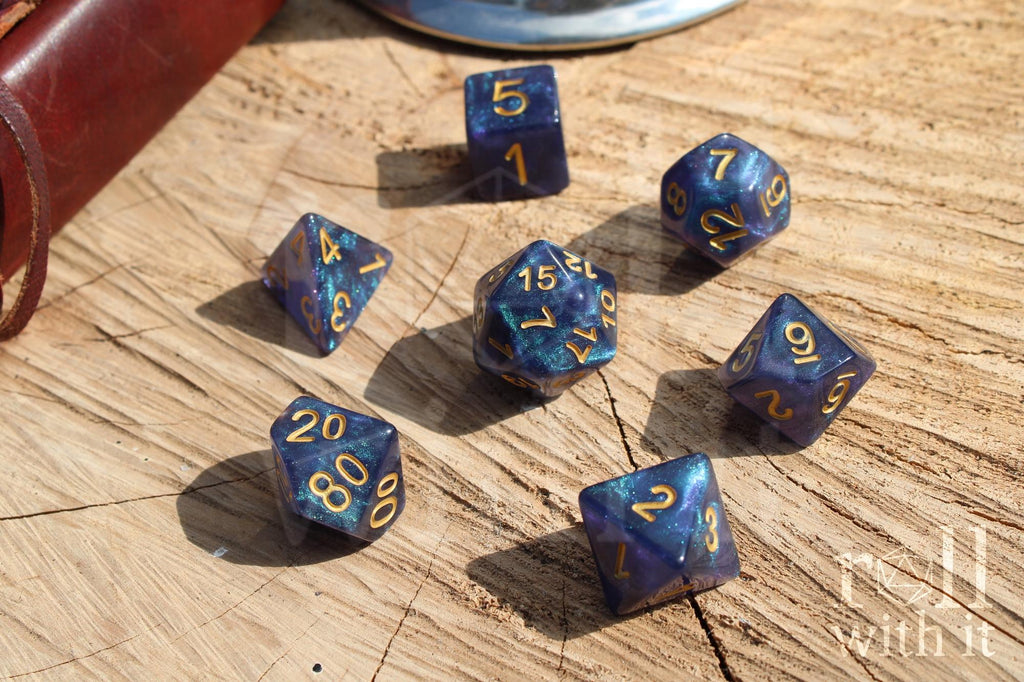 Deep blue and glittery polyhedral roleplaying dice with gold numbers on a wooden surface