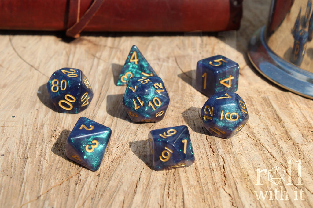 Deep blue and glittery polyhedral roleplaying dice with gold numbers on a wooden surface