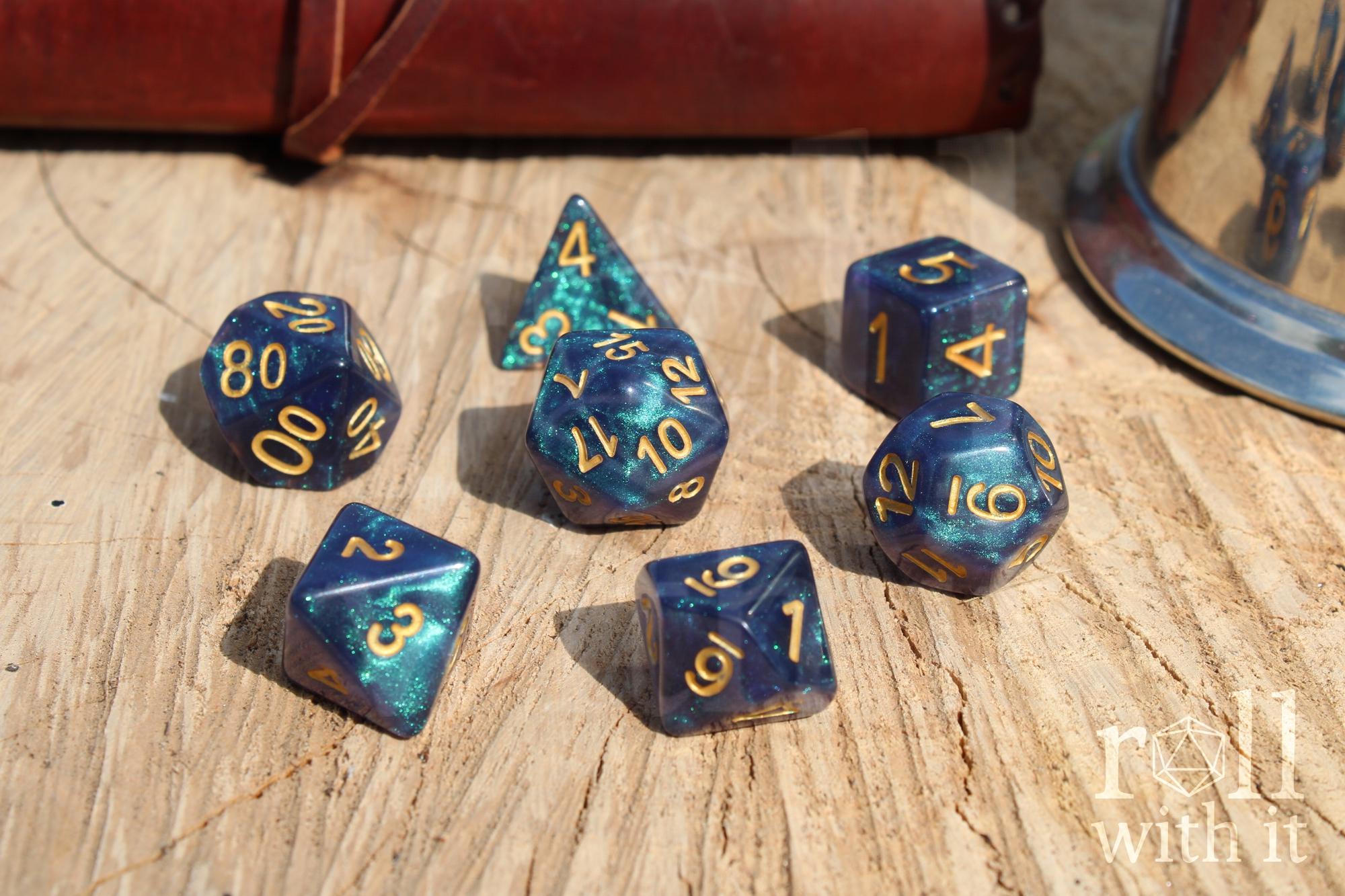 Deep blue and glittery polyhedral roleplaying dice with gold numbers on a wooden surface