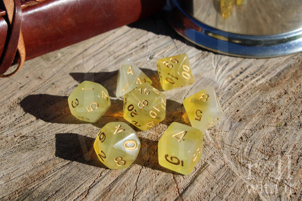 Set of translucent yellow polyhedral dice with gold numbers on a wooden surface.