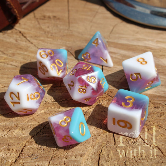 Set of colorful layered ice cream themed pink white blue shiny polyhedral dice on a wooden surface