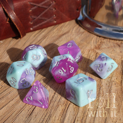 Set of purple and light blue polyhedral dice on a wooden surface with 'roll with it' branding.