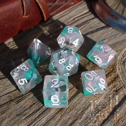 Set of teal and clear bright shiny polyhedral dice with white numbers on a wooden surface