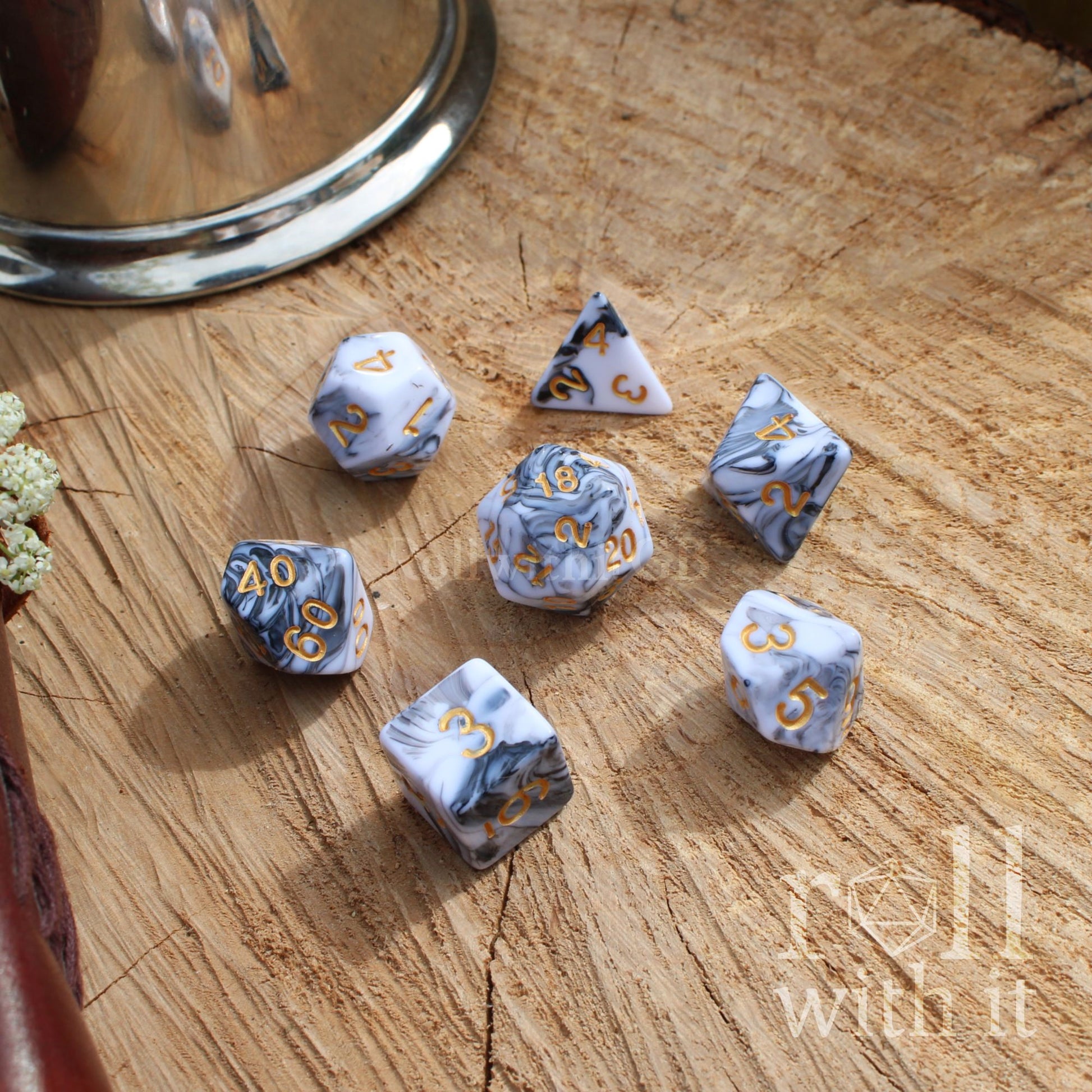 Set of dice with grey and white mixed marble patterns on a wooden surface, featuring the text 'roll with it'.