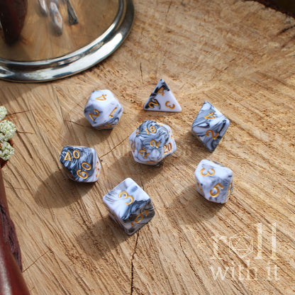 Set of dice with grey and white mixed marble patterns on a wooden surface, featuring the text 'roll with it'.