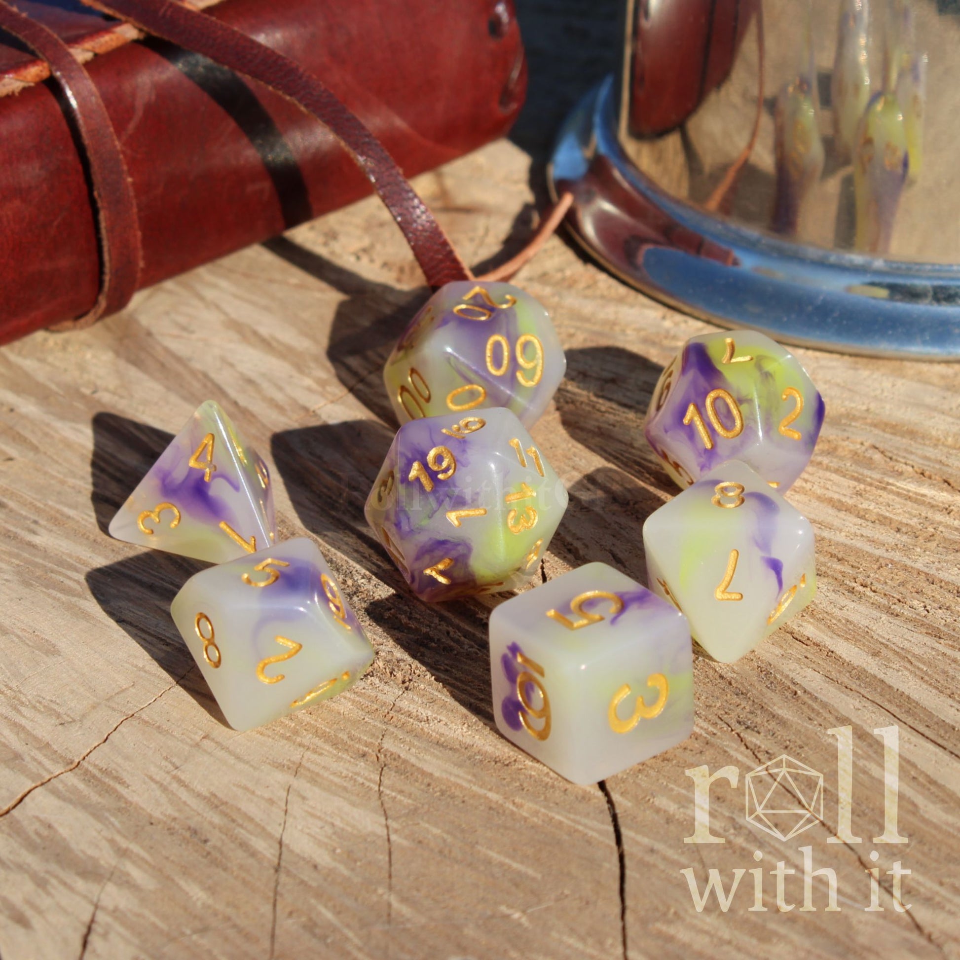 Set of purple green spring milky dice with purple and gold numbers on a wooden surface, featuring the brand 'roll with it'.