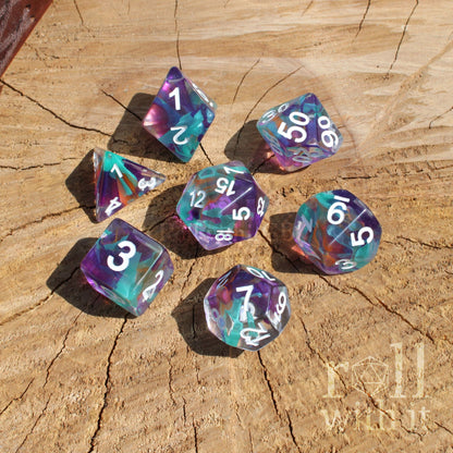 Set of colorful mixed rainbow cool purple turquoise polyhedral diceset on a wooden surface with 'roll with it' branding.