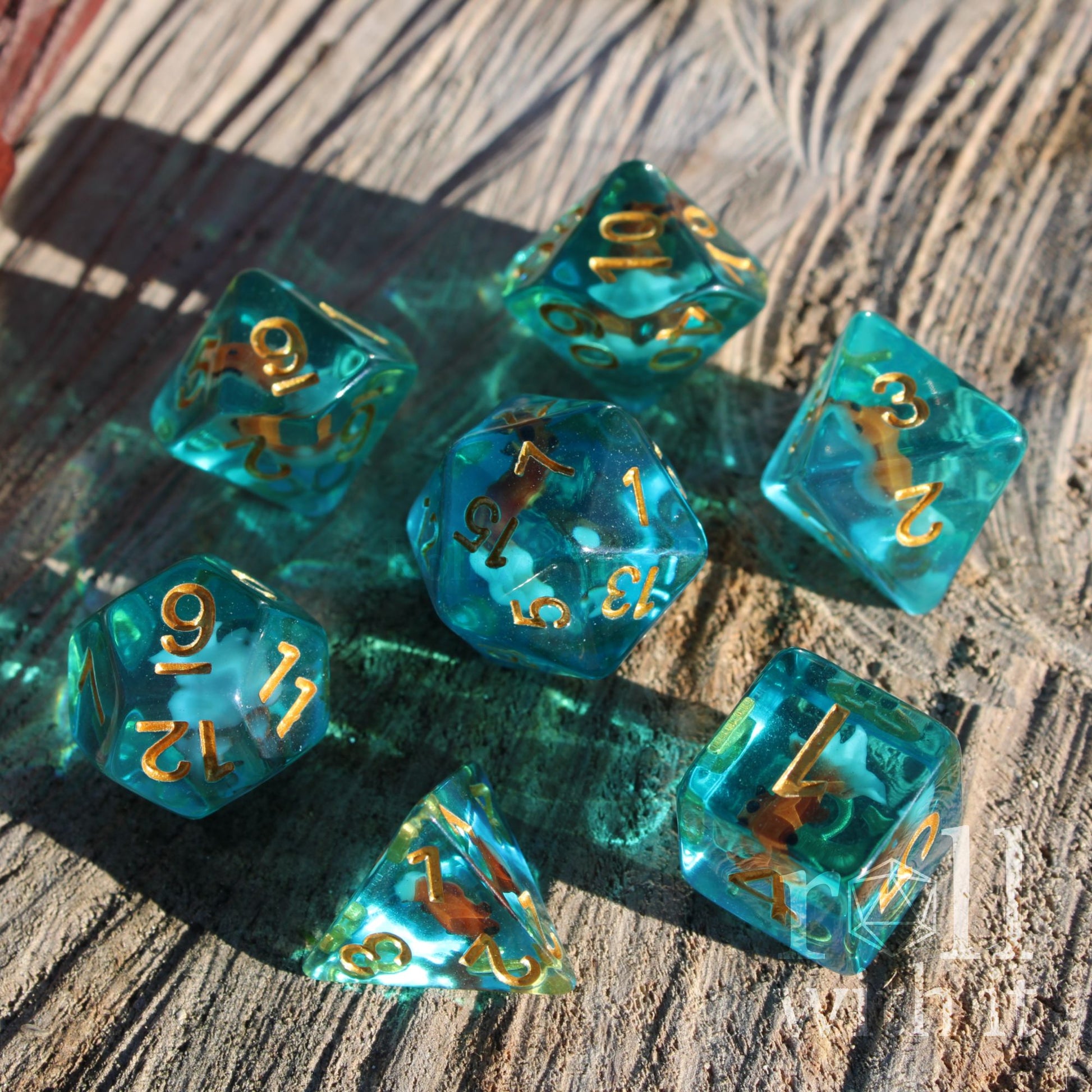Set of crystal clear ocean blue dice with gold numbers on a wooden surface