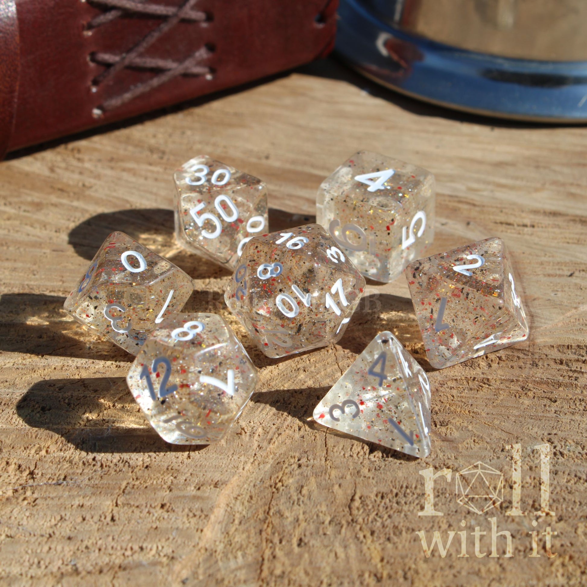 Clear speckled orange black dice set with numbers on a wooden surface, featuring the 'roll with it' logo.