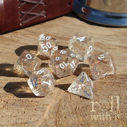 Clear speckled orange black dice set with numbers on a wooden surface, featuring the 'roll with it' logo.