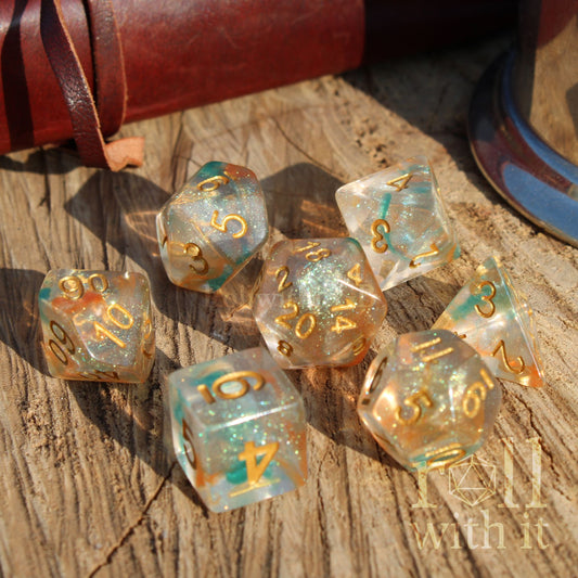 Set of shiny glitter filled orange green dice with gold numbers on a wooden surface, featuring the brand 'Roll with It'.