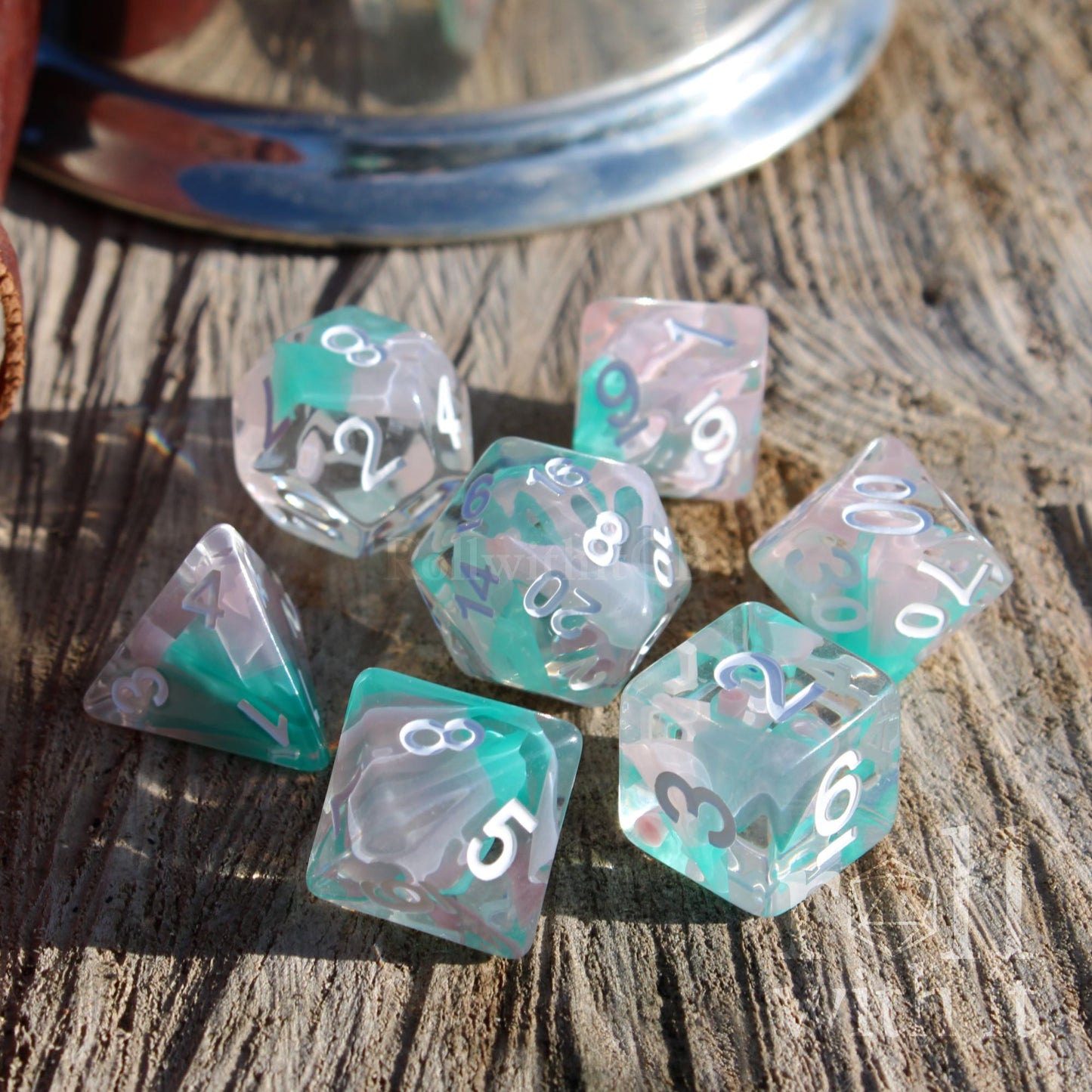 Set of teal and clear white mixed swirling ribbon polyhedral dice on a wooden surface