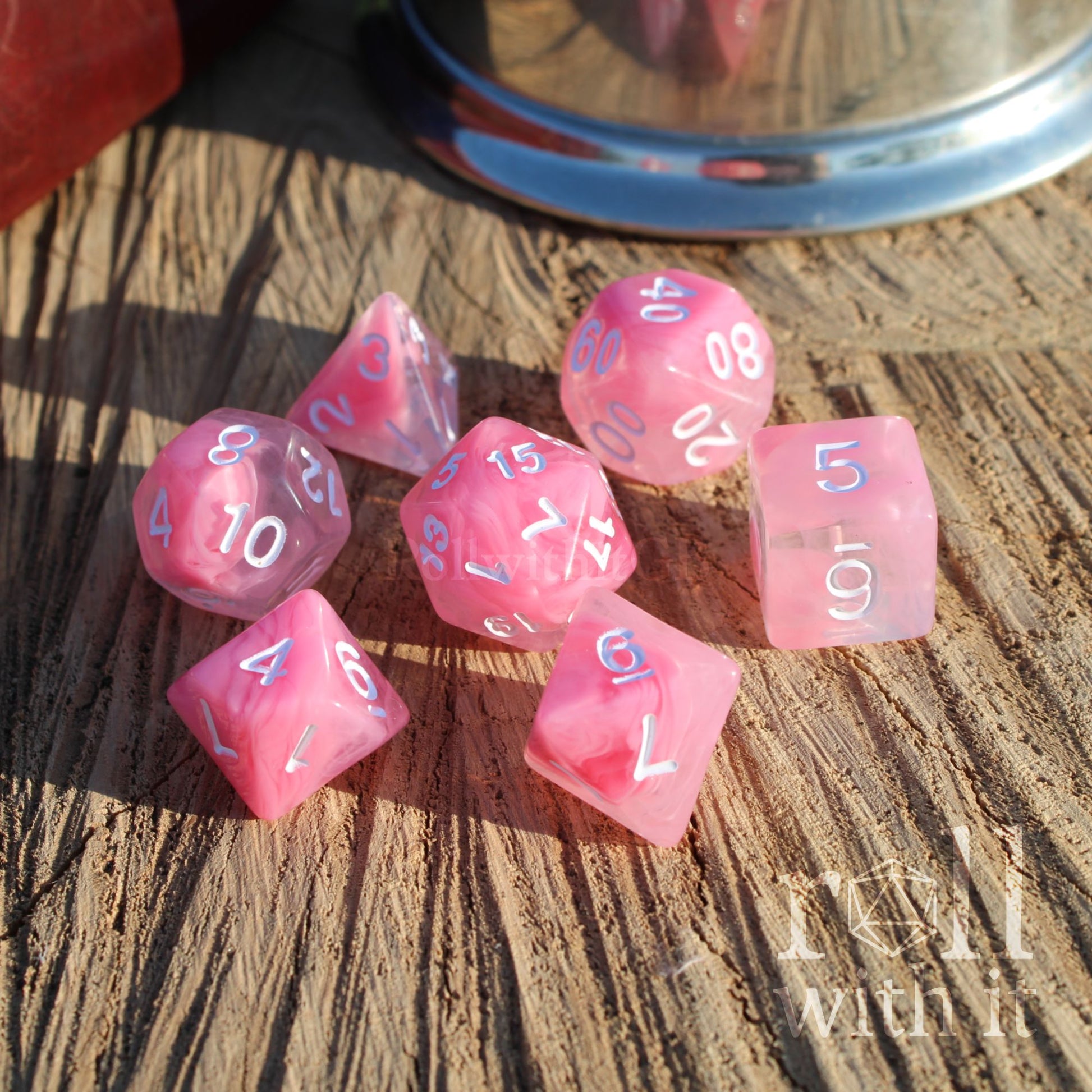 A set of 7 cute pink cloudy aesthetic polyhedral RPG on a wooden surface with white numbers