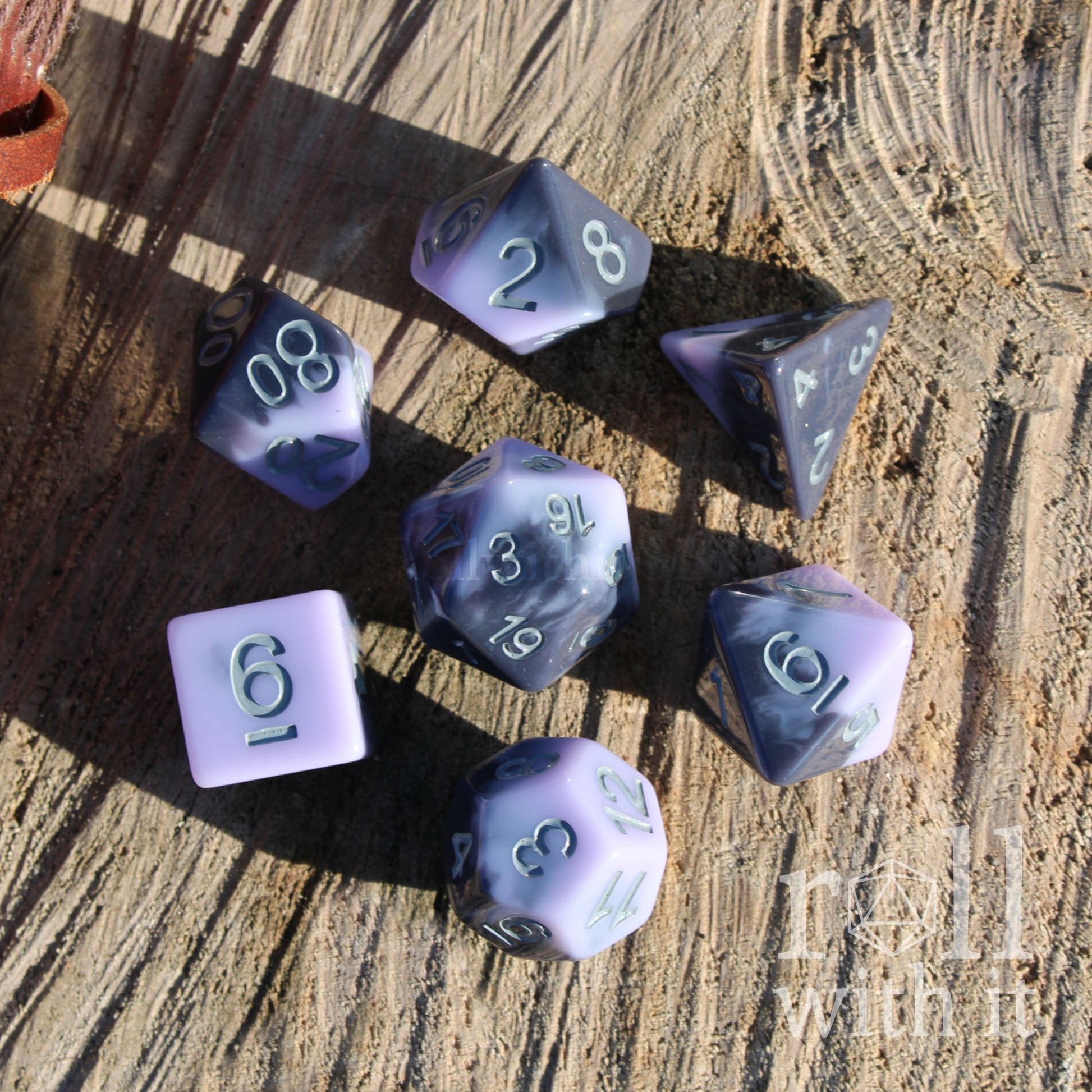 Set of purple and black shiny polyhedral dice on a wooden surface
