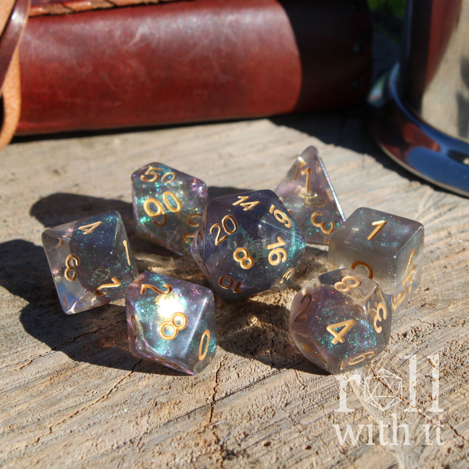 Set view of glitter filled space theme polyhedral tabletop playing dice on a wooden surface with golden gears inside