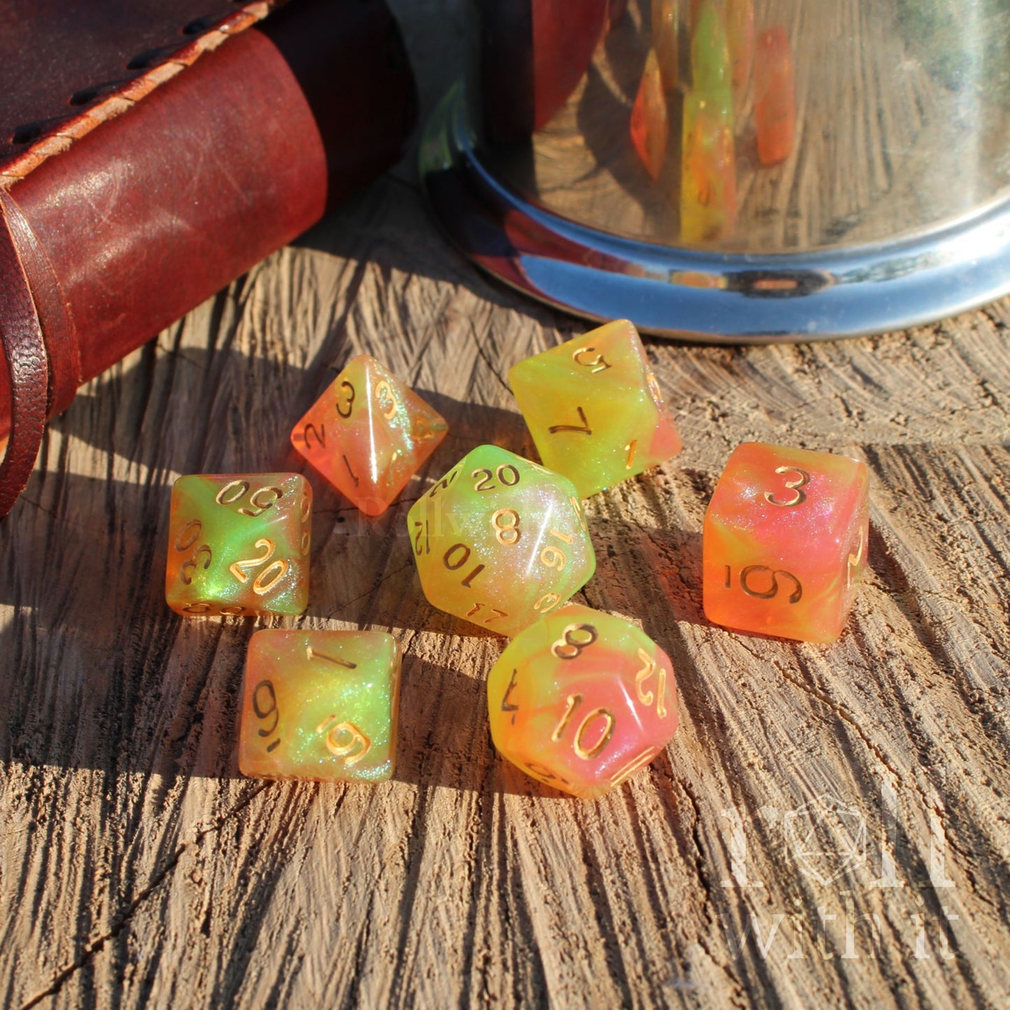 Set of colorful cute green pink dice on a wooden surface with a leather case and glass container in the background.