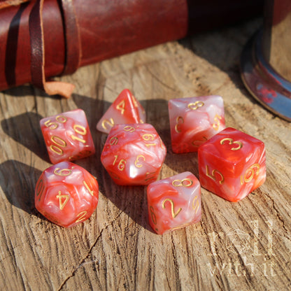 Set of red and pearl dice with gold numbers on a wooden surface