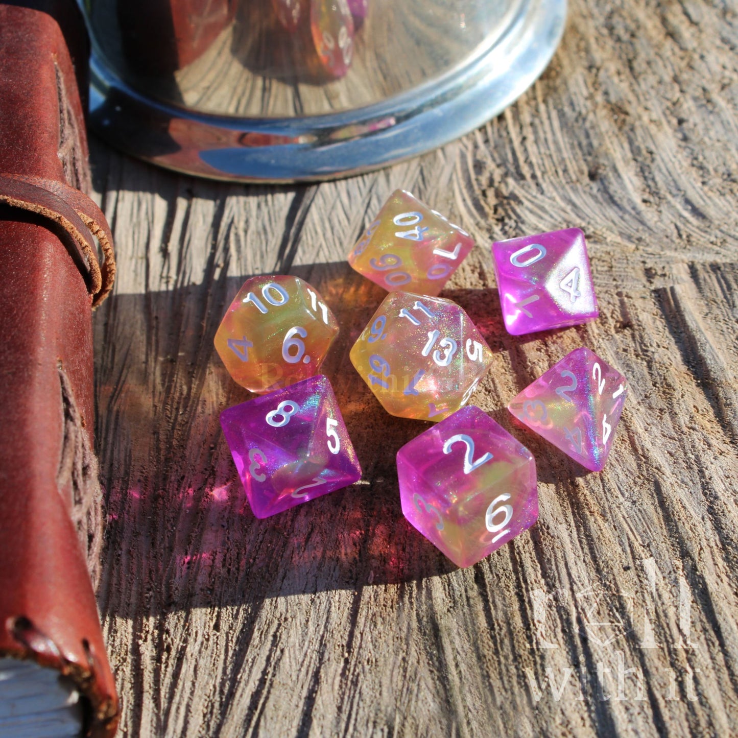 Set of colorful pink yellow polyhedral dice on a wooden surface
