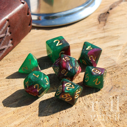 Set of poison green and purple polyhedral dice with gold numbers on a wooden surface.