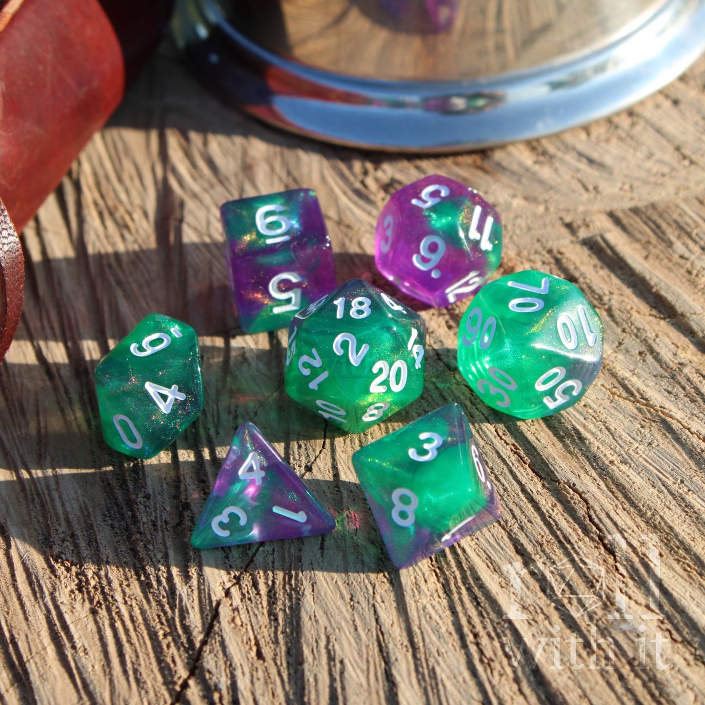 Set of green and purple glittering polyhedral dice on a wooden surface