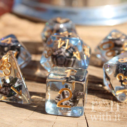 Close side view of 7 pirate ship dice with a miniature ship inside on a blue glitter sea layer