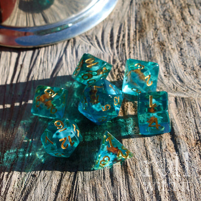 Set of teal blue polyhedral dice with gold numbers on a wooden surface
