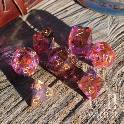 Set of pink and purple dice casting light with gold numbers on a wooden surface