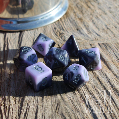 Purple and black cute pastel gothpolyhedral dice set on a wooden surface