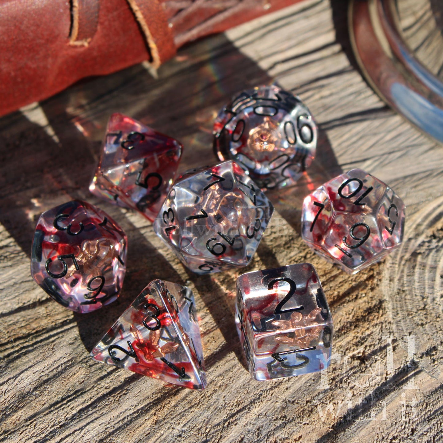 Set of transparent rogue blood dagger dice with red and black numbers on a wooden surface