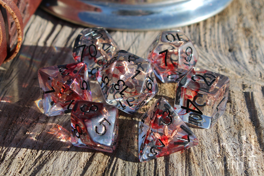 Set of transparent dice with red and black numbers on a wooden surface with rogues daggers inside
