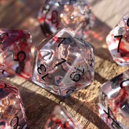 Set of transparent dice with red and black numbers on a wooden surface with rogues daggers inside