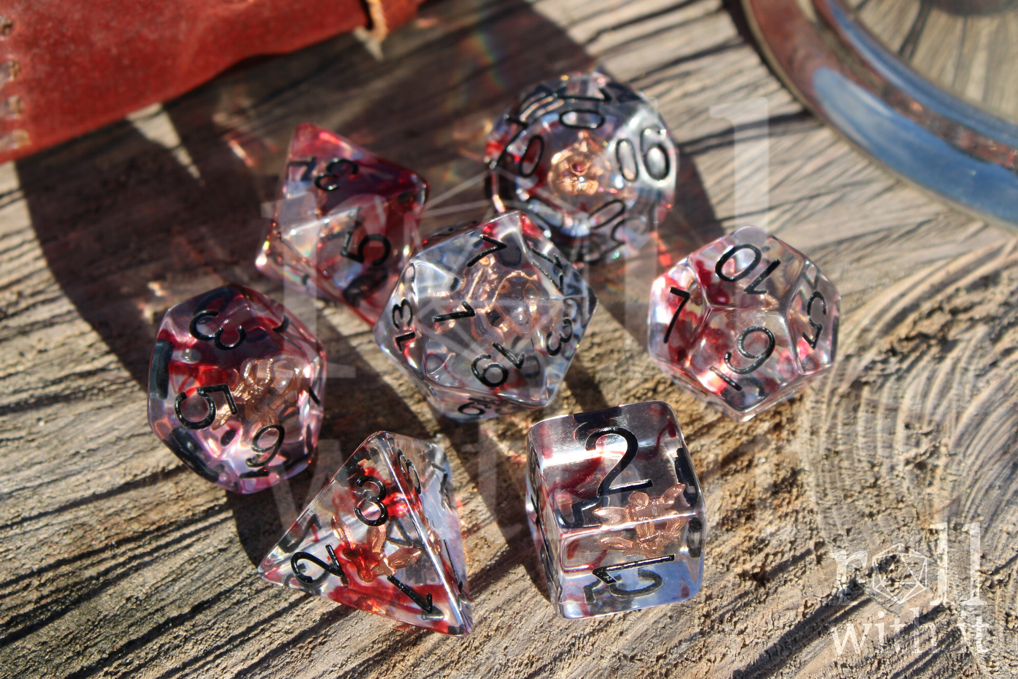 Set of transparent dice with red and black numbers on a wooden surface with rogues daggers inside
