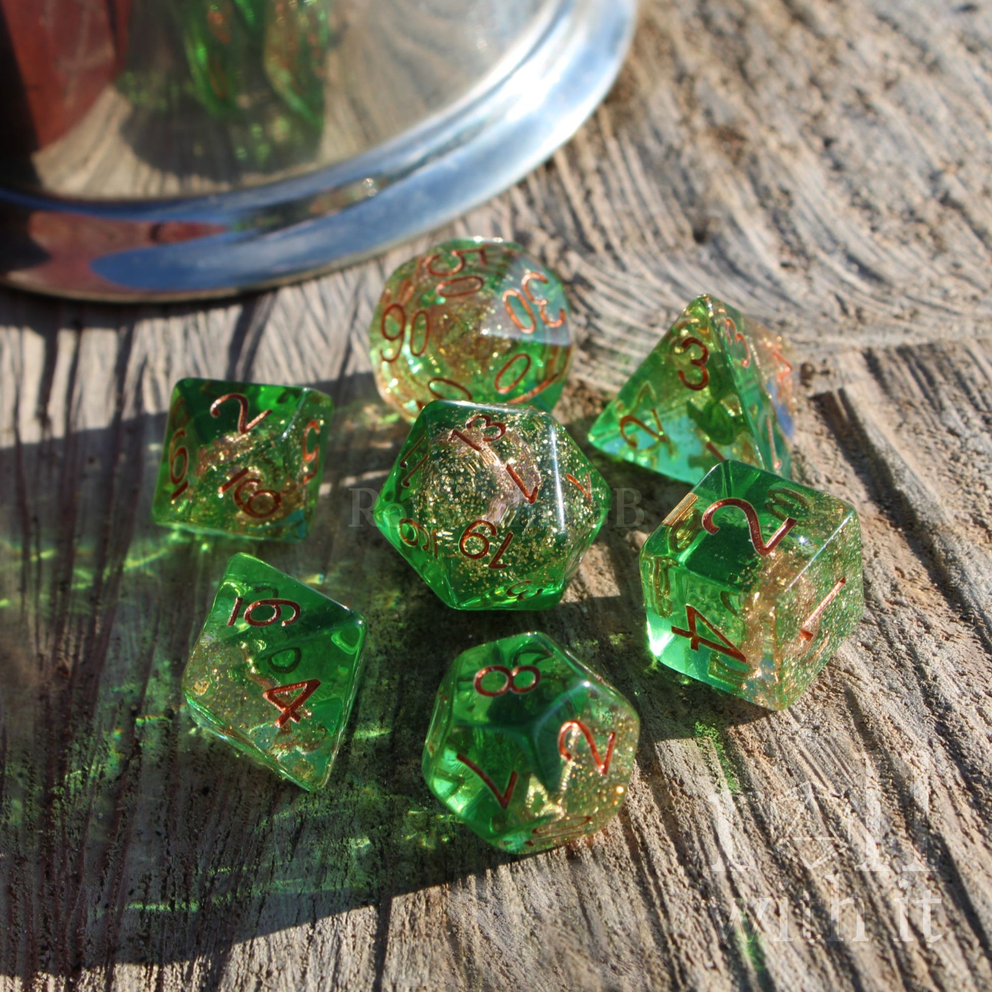 Set of green dice with glitter and copper sea anchor rope gold numbers on a wooden surface
