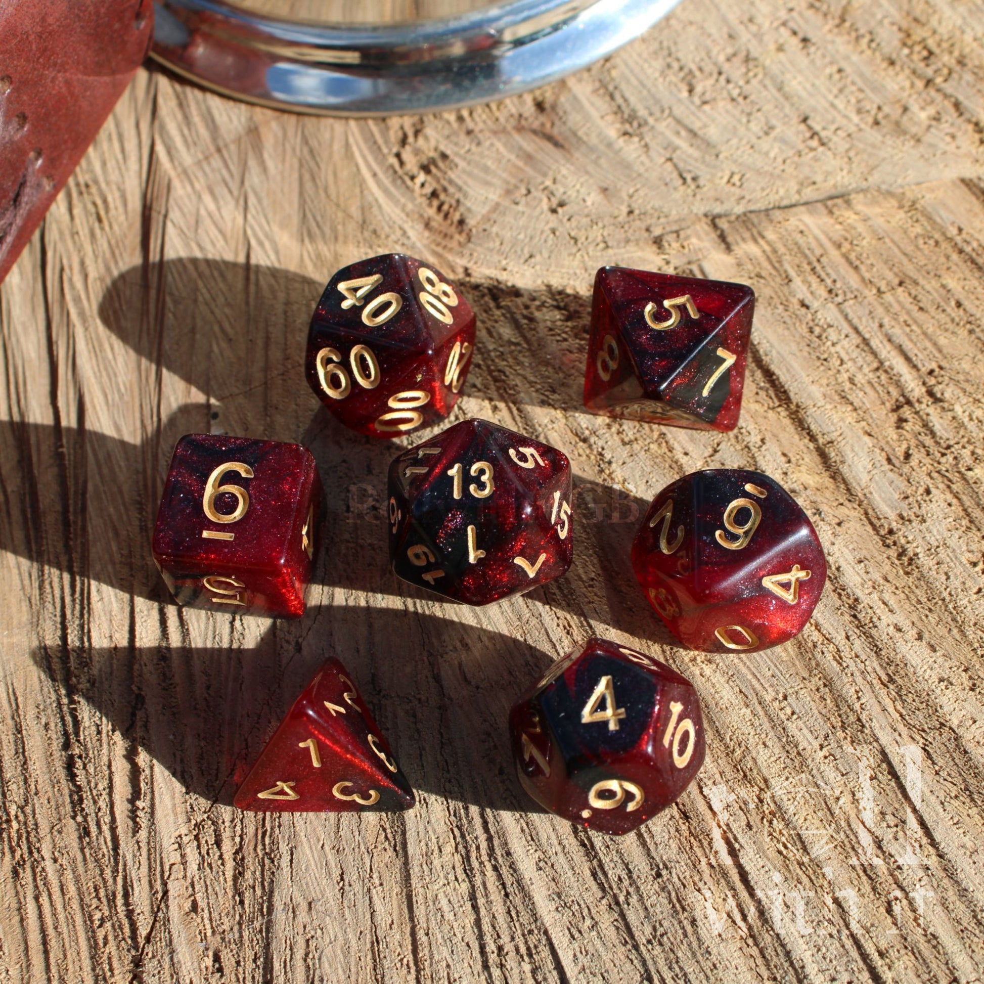 Set of red polyhedral dice with gold numbers on a wooden surface