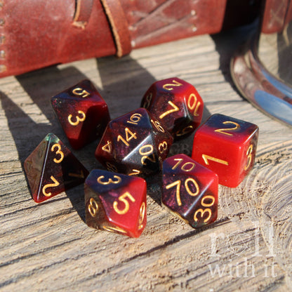 Set of polyhedral dice with red, blue, and black colors on a wooden surface.