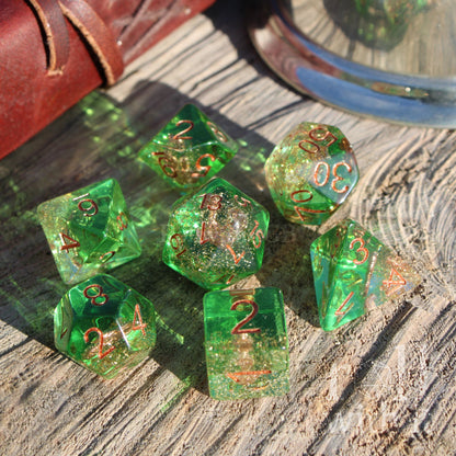Set of green sailor themed polyhedral dice with gold numbers on a wooden surface