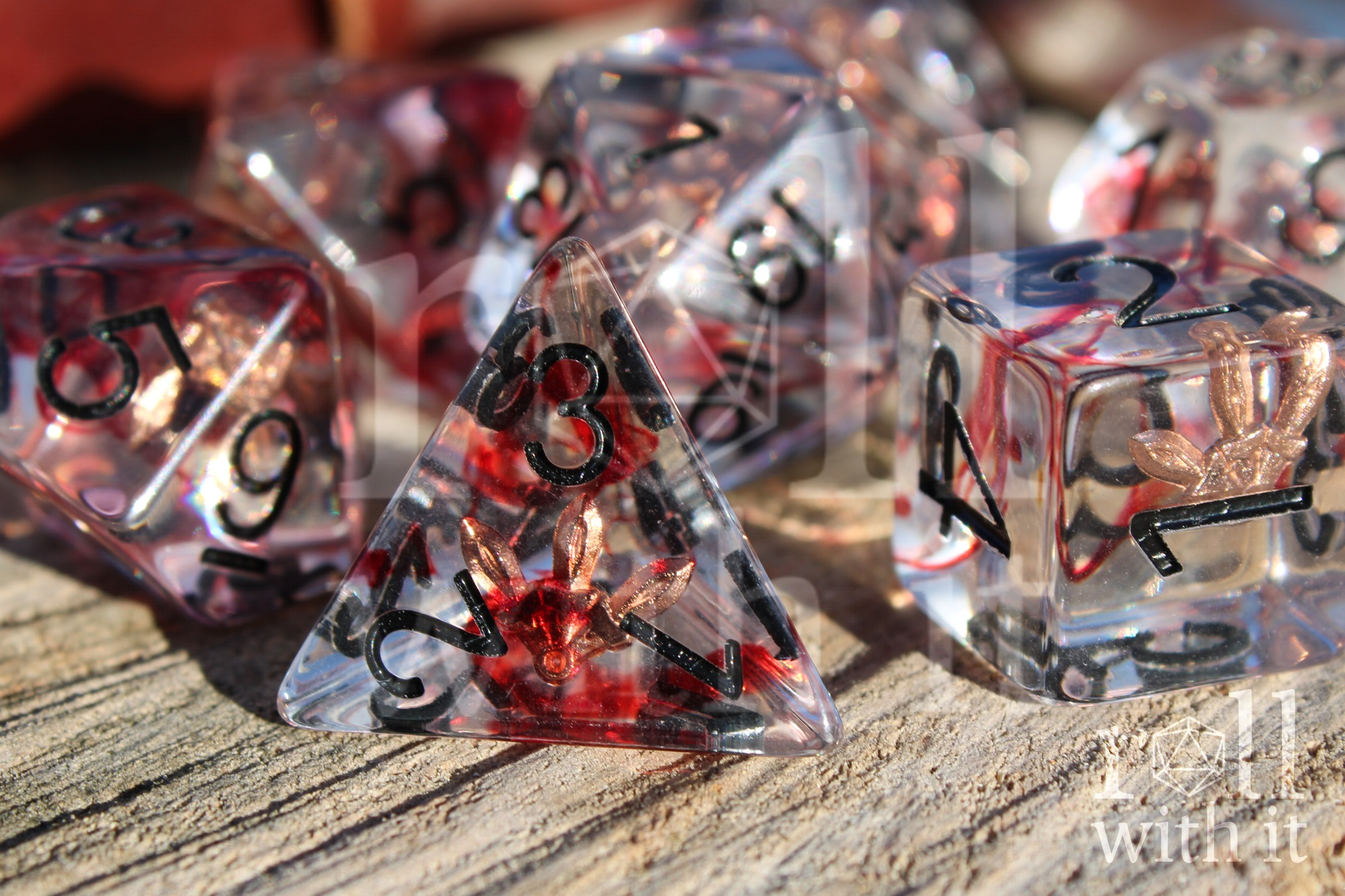 Set of transparent polyhedral dice with red and black numbers on a wooden surface with rogues daggers inside