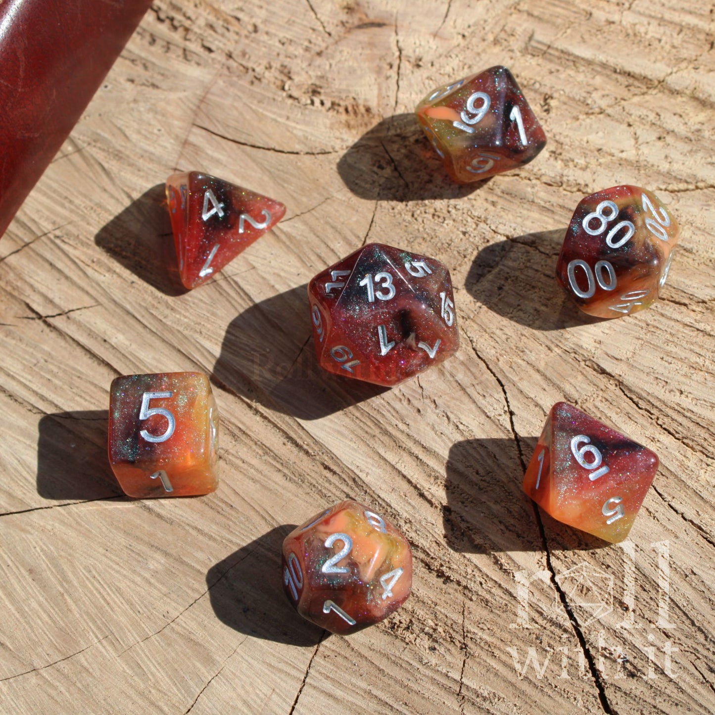 Set of shimmering black orange yellow pumpkin glitter filled polyhedral dice on a wooden surface