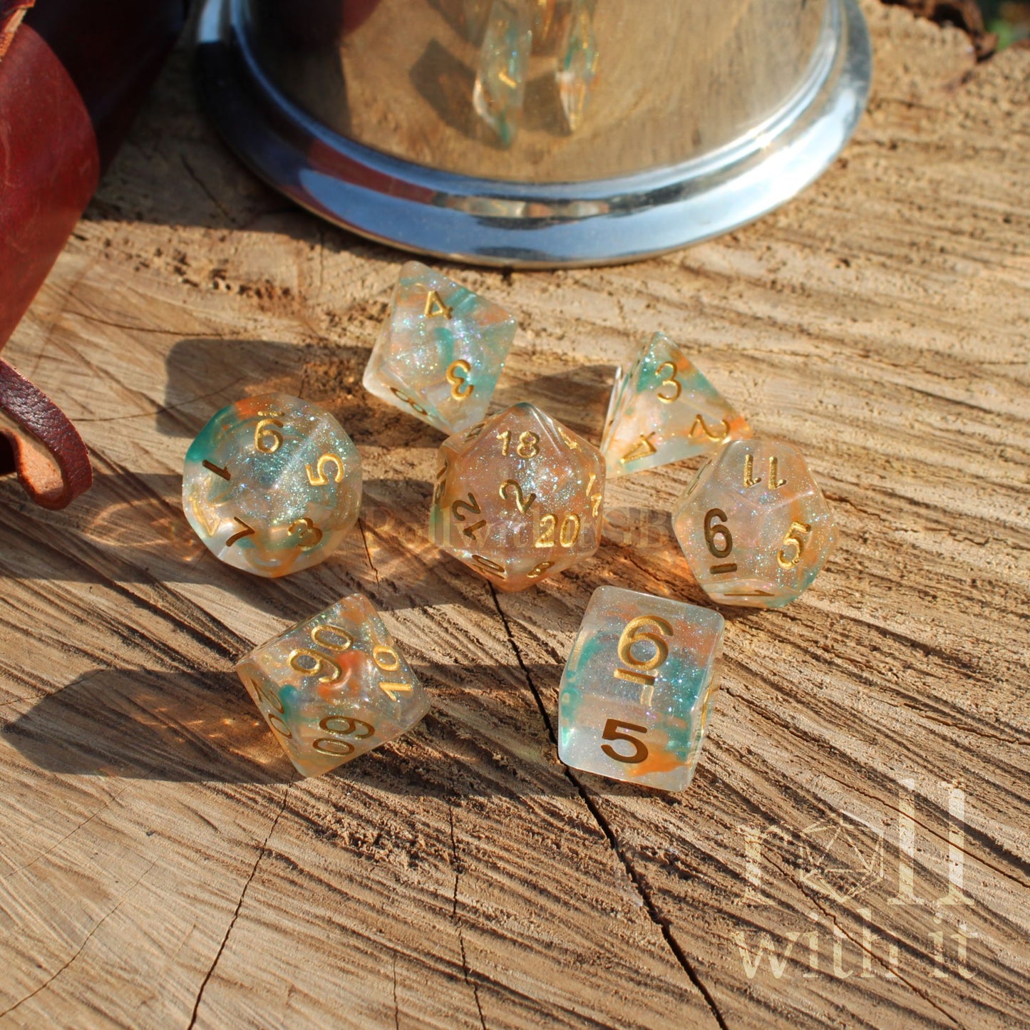 Set of shiny green teal orange shimmering dice with gold numbers on a wooden surface
