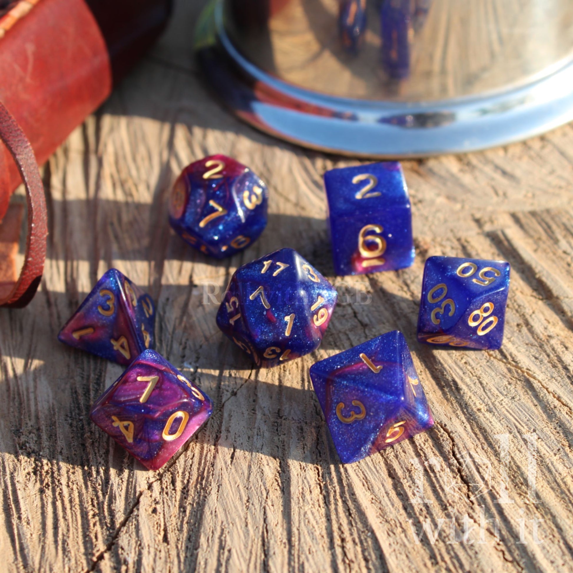 Set of blue and purple glittery reflective polyhedral dice on a wooden surface