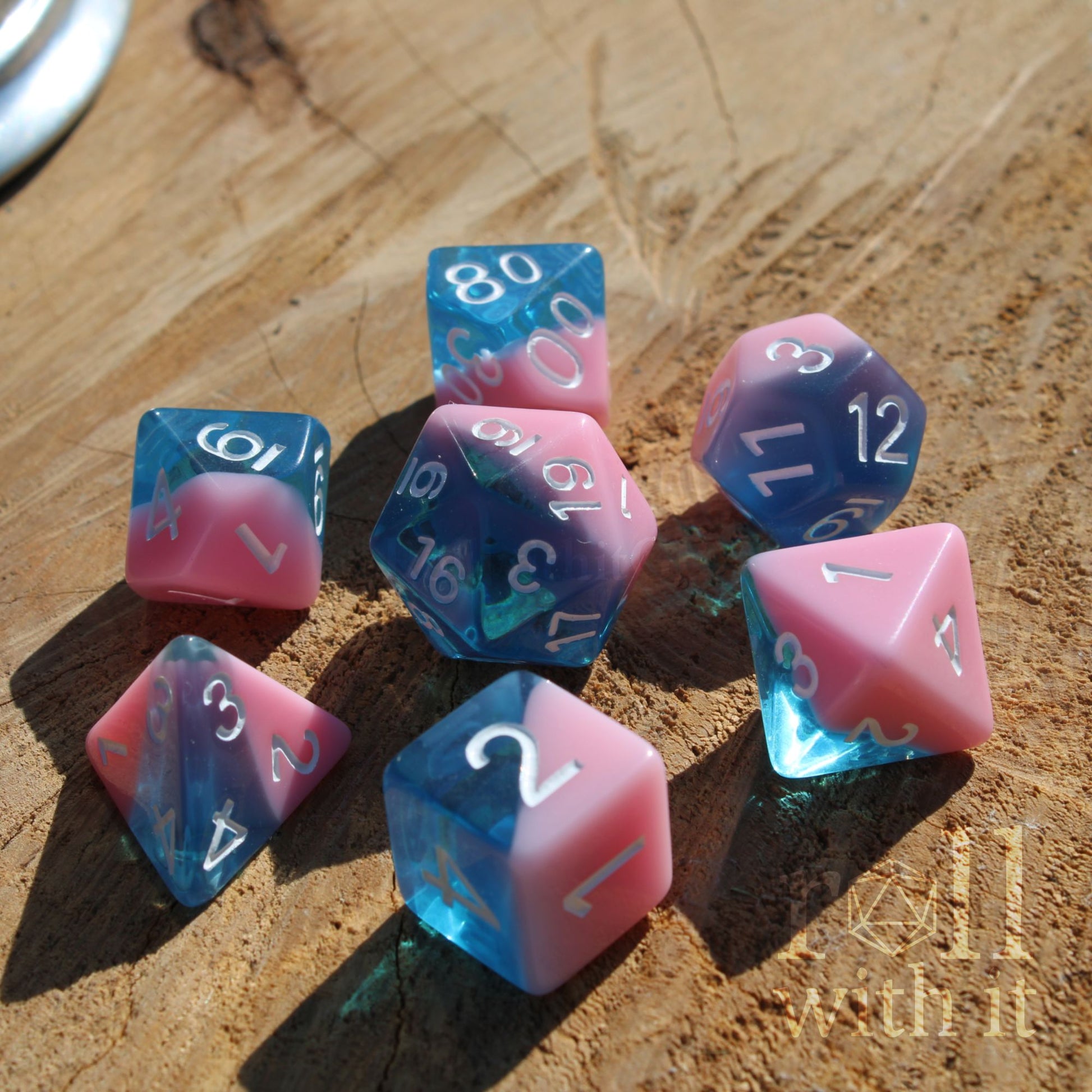 Set of shiny pink and blue polyhedral dice on a wooden surface