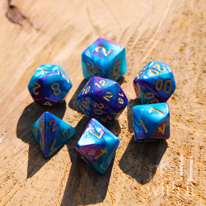 Set of blue and purple shiny mixed polyhedral dice with gold numbers on a wooden surface