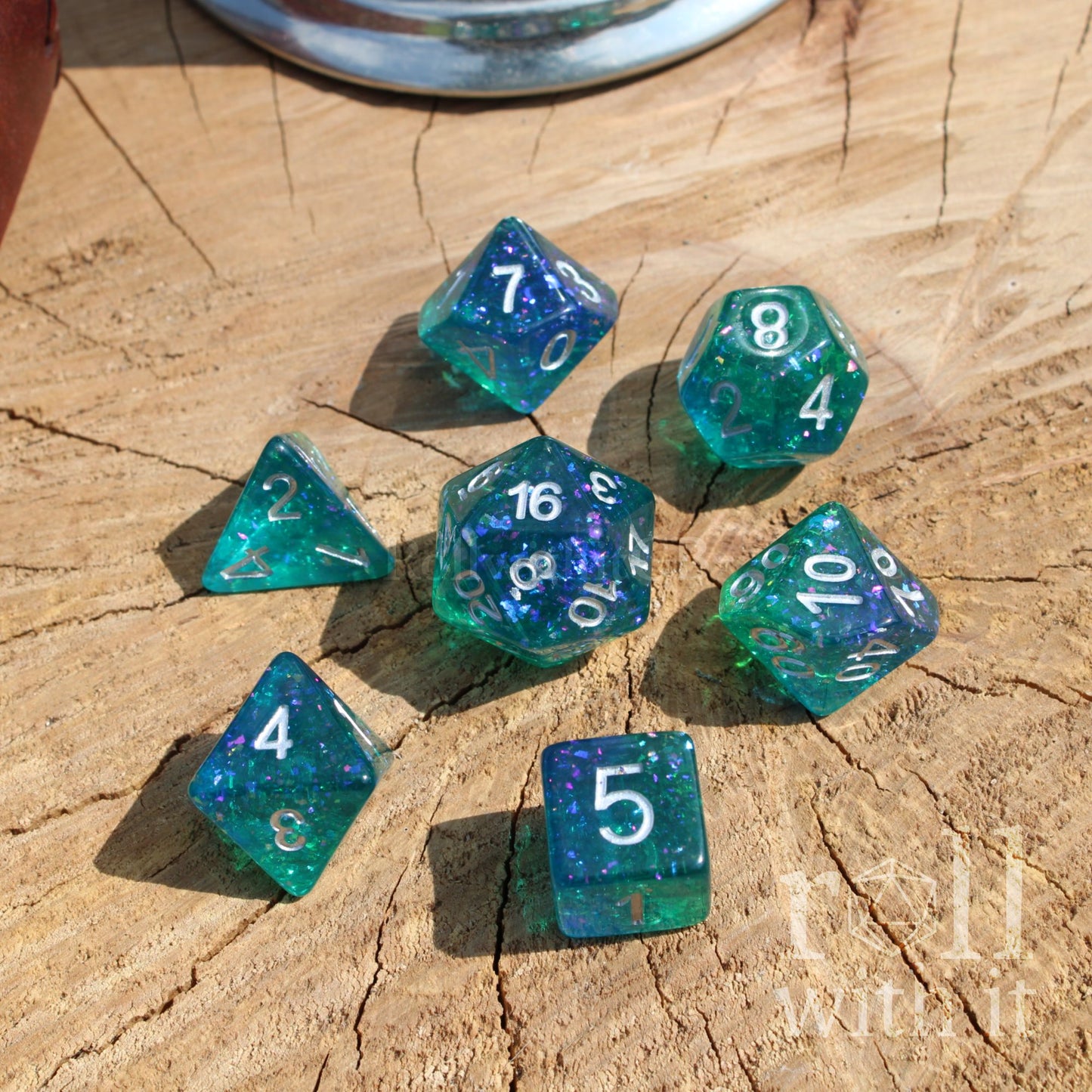 Set of green blue silver gold foil polyhedral dice on a wooden surface