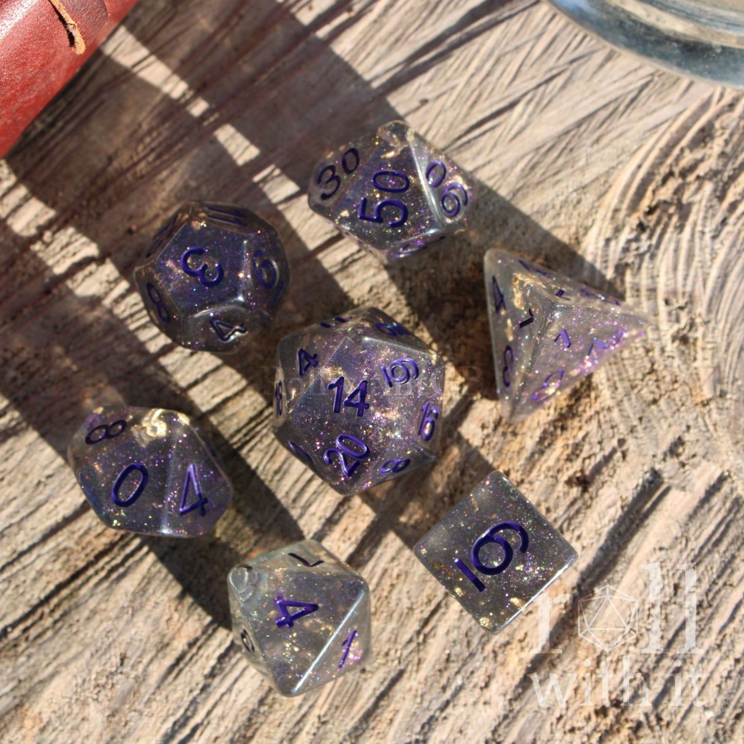 Set of glittery grey gold foil purple polyhedral dice on a wooden surface