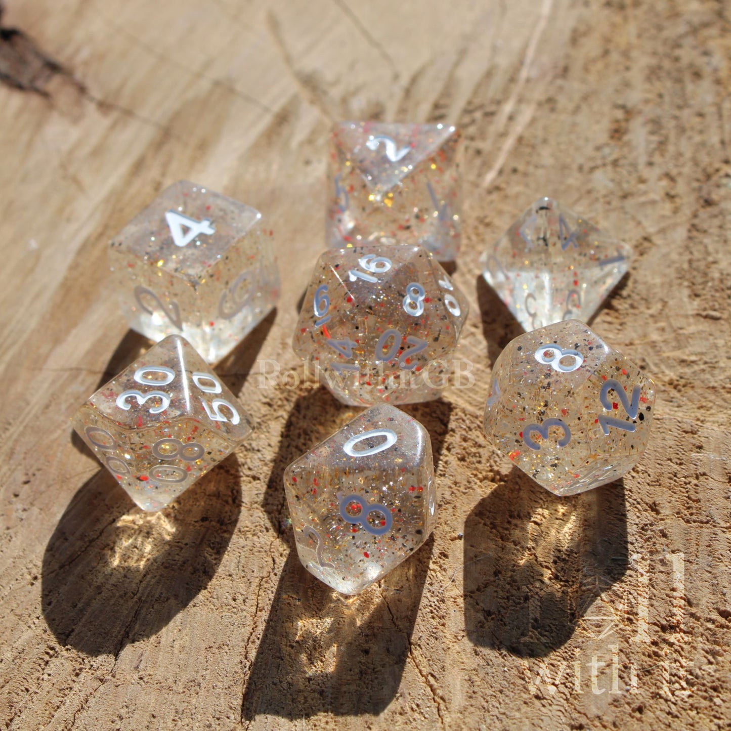 Set of clear speckled orange black dnd polyhedral dice with numbers on a wooden surface