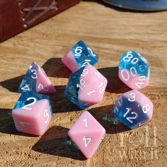 Set of pink milkshake coloured and blue polyhedral dice on a wooden surface