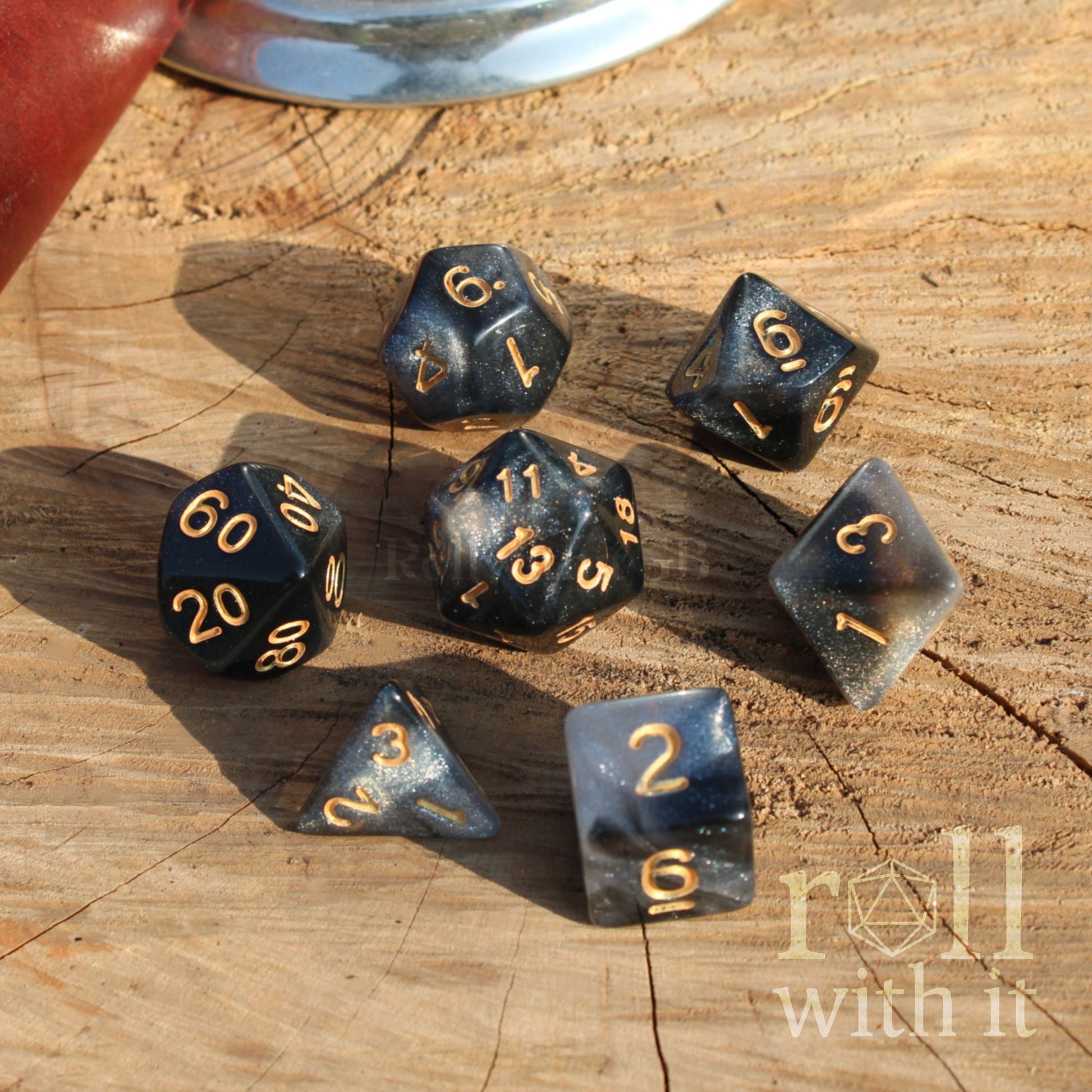 Set of polyhedral dice on a wooden surface with 'roll with it' branding.
